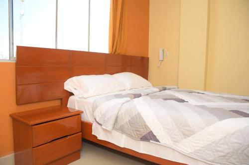 a bedroom with a large bed with a wooden headboard at Hostal El Gran Marquez G&J in Urbanizacion Buenos Aires