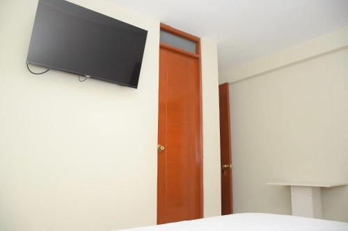 1 dormitorio con TV de pantalla plana en la pared en Hostal El Gran Marquez G&J en Urbanizacion Buenos Aires