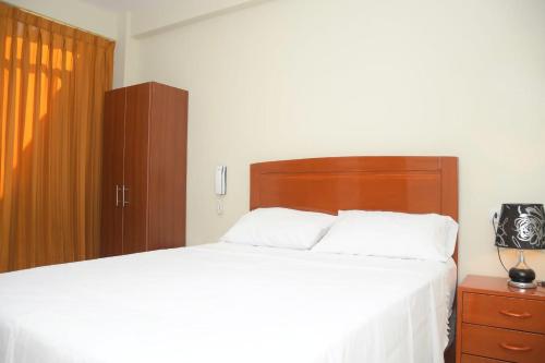 a bedroom with a large bed with a wooden headboard at Hostal El Gran Marquez G&J in Urbanizacion Buenos Aires