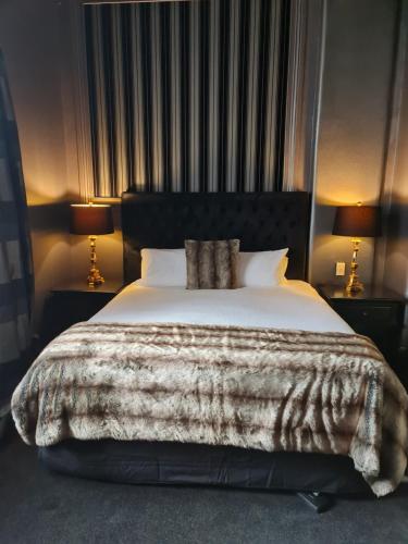 a large bed in a bedroom with two lamps at Hotel D'urville Blenheim in Blenheim