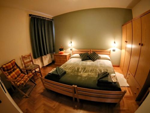 um quarto com uma cama grande e uma cadeira em Il Balcone Delle Alpi em Bormio