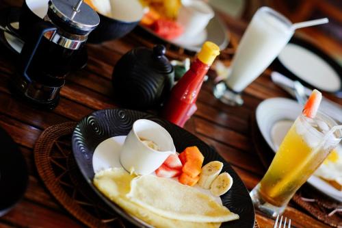 a plate of food with eggs and fruit on a table at Ellies Hotel in Nusa Dua