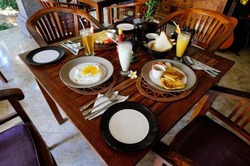 a wooden table with eggs and toast on it at Ellies Hotel in Nusa Dua