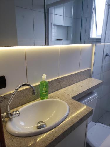 a bathroom sink with a green soap bottle on it at Apartamento agradável em Ubatuba in Ubatuba