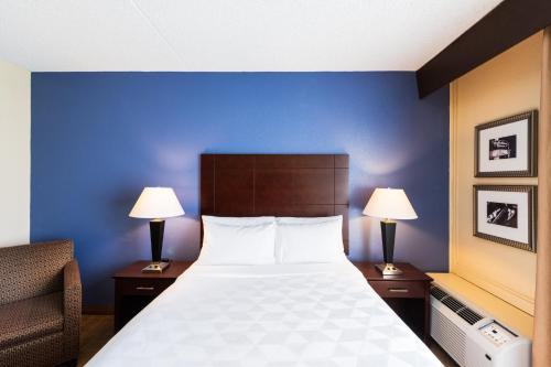 a bedroom with a bed and two lamps and a chair at Holiday Inn South Plainfield-Piscataway by IHG in South Plainfield