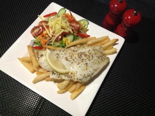a white plate with fish and french fries and a salad at Parkside Motel Ayr in Ayr