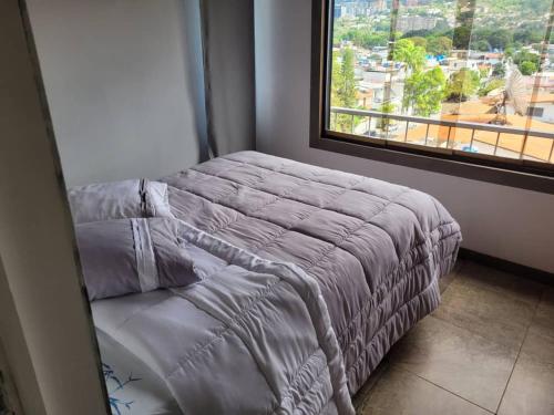 Cama en habitación con ventana grande en Apartamento tipo estudio, en Caracas