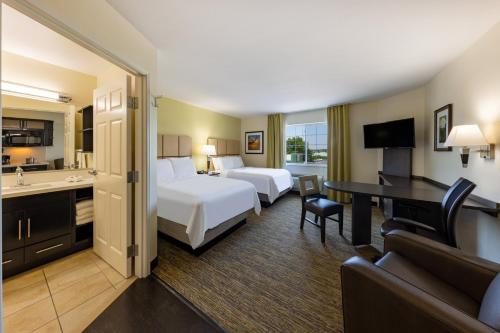 ein Hotelzimmer mit 2 Betten und einem Schreibtisch in der Unterkunft Candlewood Suites Springfield South, an IHG Hotel in Springfield