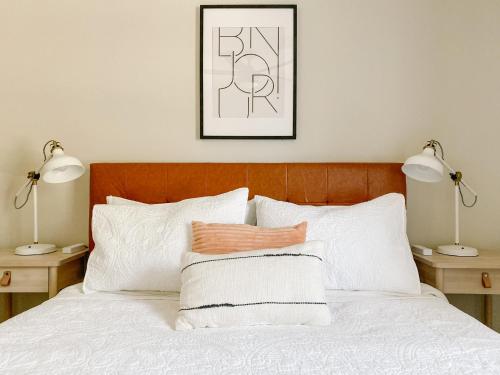 a bedroom with a bed with white pillows and two lamps at The Ruby - Modern Updated 4/2 Home Near ACU in Abilene