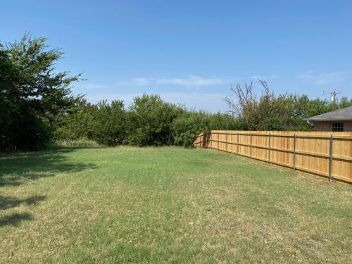 a large yard with a fence and trees at The Ruby - Modern Updated 4/2 Home Near ACU in Abilene