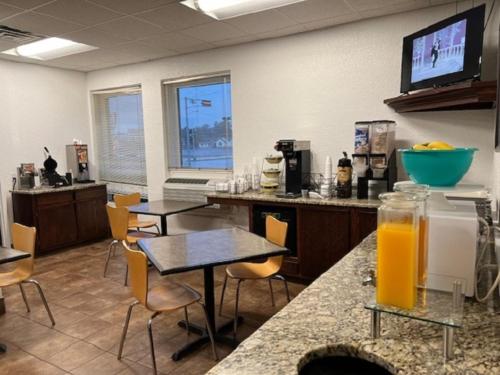 un bureau avec des tables et des chaises et un comptoir avec du jus d'orange dans l'établissement Posh Inn & Suites, à Wisconsin Rapids