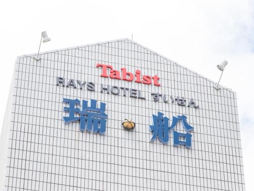 a building with a sign on the side of it at Tabist Rays Hotel Suisen in Miyazaki