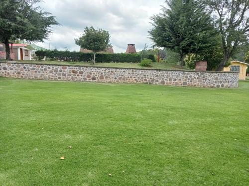 a stone wall in a yard with green grass at Finca Marix, Villa del Carbón in Villa del Carbón