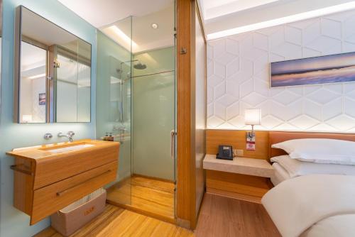 a bathroom with a bed and a sink and a shower at H-hotel Riverside in Chengdu
