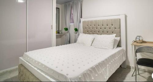 1 dormitorio blanco con 1 cama blanca grande y cabecero blanco en Epic Pointe 2A, en Cartagena de Indias