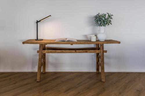 a wooden table with a lamp and a plant on it at Fairfield House 17 Rookery Road in Emu Bay