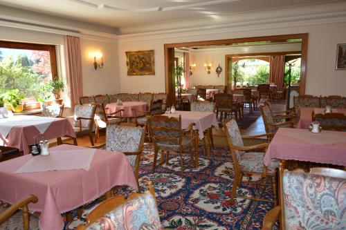 uma sala de jantar com mesas e cadeiras com toalhas de mesa cor-de-rosa em Hotel Garni Sonnenhof em Rottach-Egern