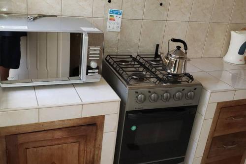 a kitchen with a stove and a microwave at Depto comodo centrico cerca a colegios;hospitales in Cochabamba