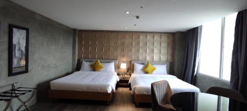 a hotel room with two beds and a chair at City Park Hotel Residences in Manila