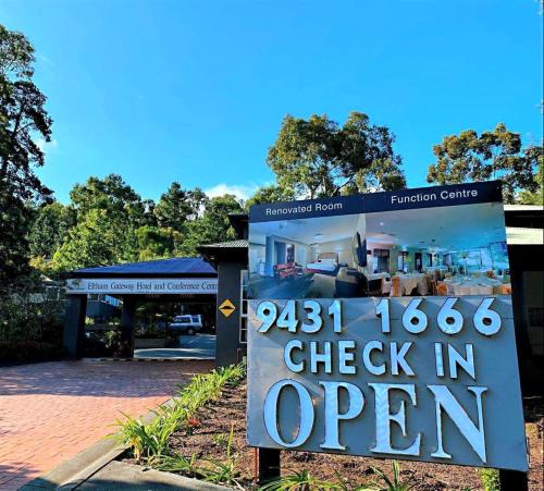 a sign that reads check in open in front of a building at Eltham Gateway Hotel & Conference Centre in Eltham