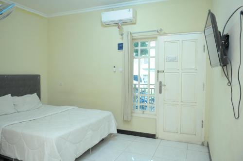 a bedroom with a white bed and a window at Griya Agnes Semarang Mitra RedDoorz in Kalibanteng-kidul