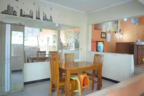 a dining room with a wooden table and chairs at Griya Agnes Semarang Mitra RedDoorz in Kalibanteng-kidul