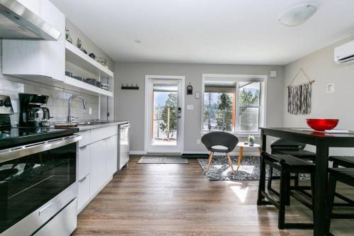 a kitchen with white cabinets and a dining table at North Shore Estates Getaway in Lake Cowichan