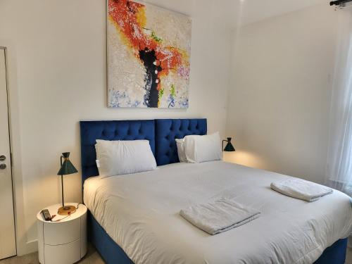 Bett mit blauem Kopfteil in einem Schlafzimmer in der Unterkunft Garland Modern 4 Bedroom Central Apartment London in Finchley