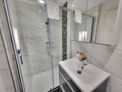 uma casa de banho branca com um lavatório e um chuveiro em Garland Modern 4 Bedroom Central Apartment London em Finchley