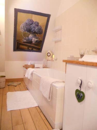 La salle de bains est pourvue d'une baignoire blanche et d'une peinture murale. dans l'établissement chambre le nid du phare avec jacuzzi, à Honfleur