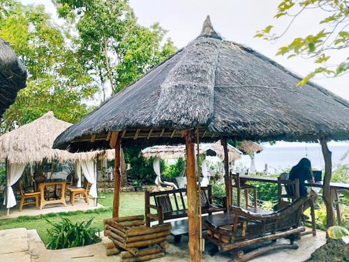 aiki hut with chairs and tables and chairs and the ocean at Tahanan Resort in San Juan