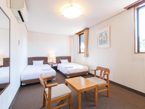 a room with two beds and a table and chairs at Tabist Business Hotel Fujiya in Emukae