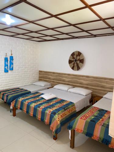 um quarto com três camas e um relógio na parede em Pousada das Gaivotas em Guaibim