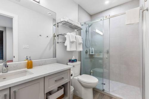 a bathroom with a toilet and a glass shower at Beach Suites in Parksville