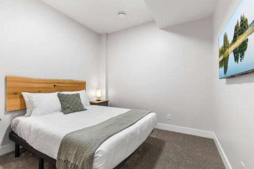 a bedroom with a white bed with a wooden headboard at Beach Suites in Parksville