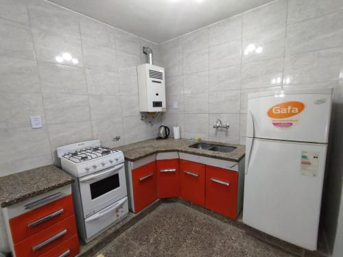 una pequeña cocina con nevera blanca y armarios rojos en Casa Barrio Sur COMODA en San Miguel de Tucumán