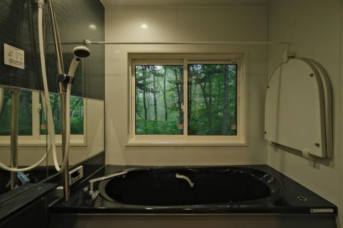 łazienka z czarną umywalką i oknem w obiekcie Fandina藤原 w mieście Azumaiokozan