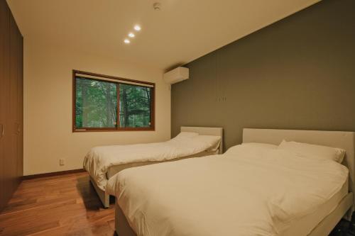 1 dormitorio con 2 camas y ventana en Fandina藤原 en Azumaiokozan
