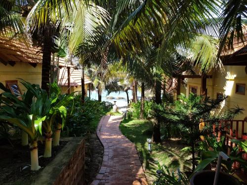 a garden with palm trees and a brick walkway at Free Beach Resort in Phu Quoc