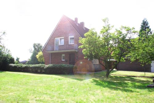 a red brick house with a tree in the yard at Haus Prilblume in Detern
