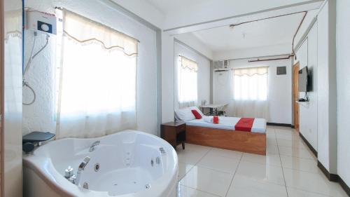 a bathroom with a tub and a bed in a room at RedDoorz near Tambo Quirino Avenue in Manila