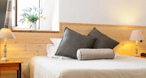 a bedroom with a bed with two pillows and a window at Hôtel La Grange Aux Marmottes in Viscos