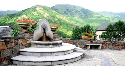 a fountain in front of a stone wall with flowers at Hôtel La Grange Aux Marmottes in Viscos