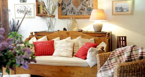 a couch with red and white pillows on it at Hôtel La Grange Aux Marmottes in Viscos
