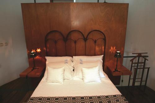 a bed with a wooden head board and white pillows at O Moinho Da Bibi in Candelária