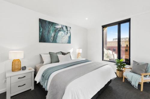 a white bedroom with a large bed and a window at Pier Point 404- Luxe on Geelong Waterfront, 2 BDRM in Geelong