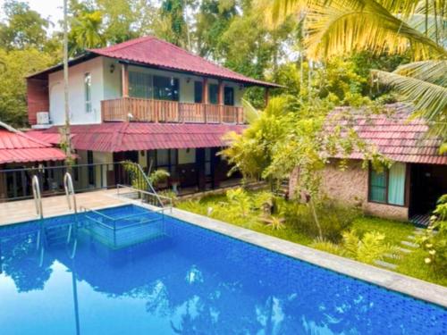 a villa with a swimming pool in front of a house at Lakefront Beach Homes in Cherai Beach