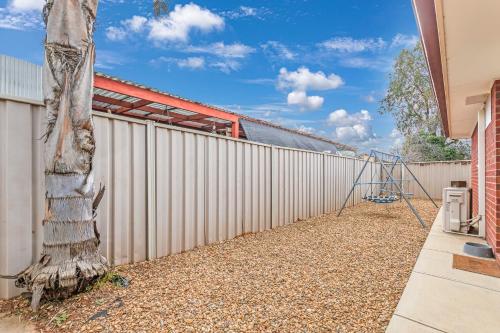 a fence with a tree next to a building at Sleepy Shackell - Echuca Moama Holiday Accommodation in Echuca