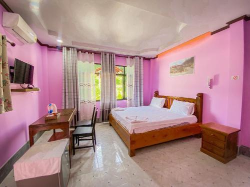 a bedroom with pink walls and a bed and a desk at Baan Rung Tawan in Ban Bang Nao