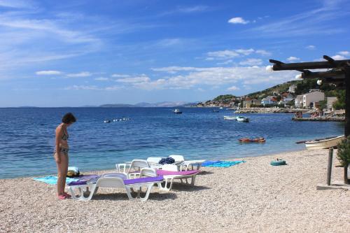 a woman standing on a beach near the water at Apartments by the sea Sumpetar, Omis - 4827 in Jesenice